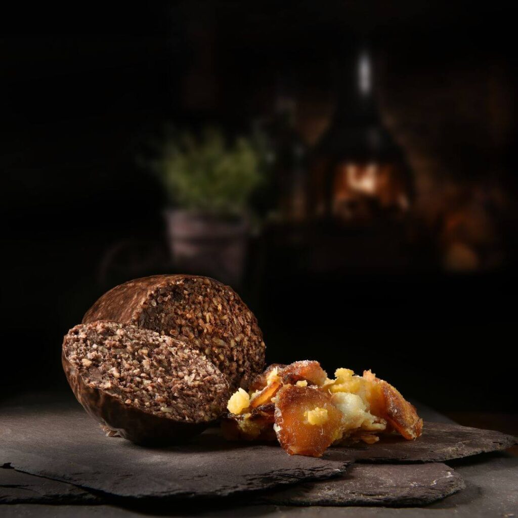 Scottish haggis on a slate serving plate against a black background, often part of a traditional breakfast in Scotland