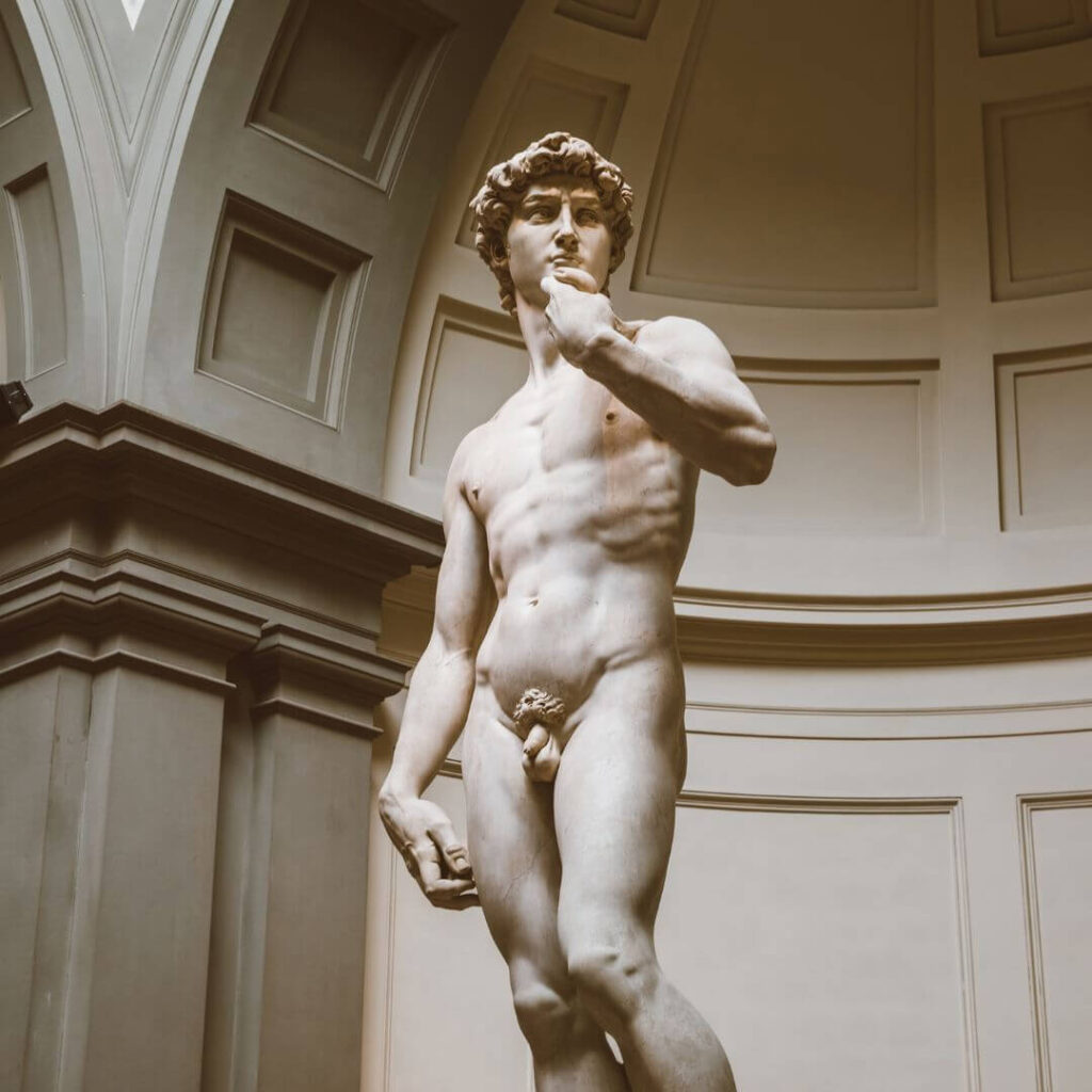 Michelangelo's David at the Accademia Galleria in Florence Italy. The nude sculpture made of white marble stands in an alcove, where it can be seen from all angles
