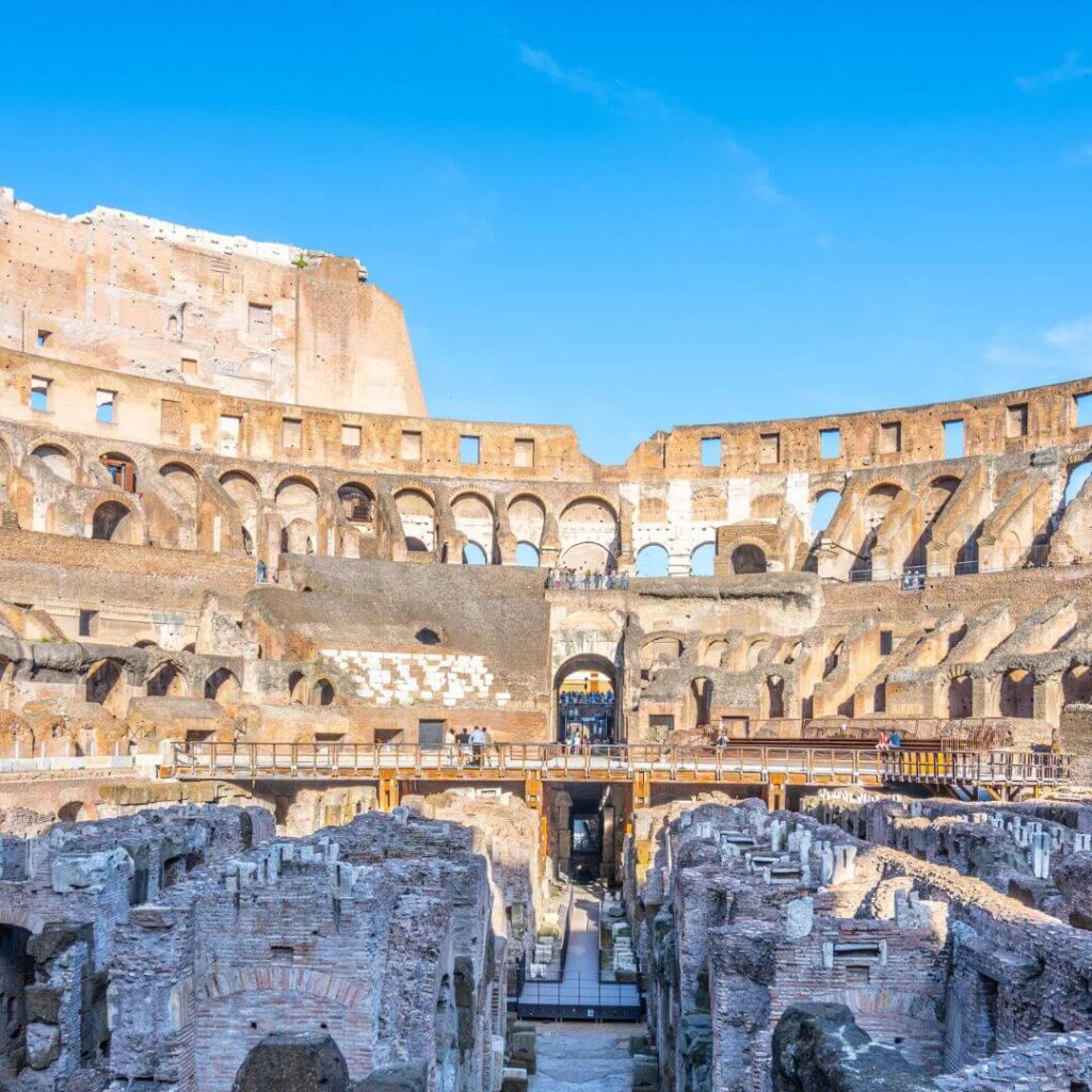 The interior of the Roman Colusseum. You can see the remnants of the rows of benches where spectators would have sat. Most of the floor is gone, allowing a view into the hypogeum under the arena.