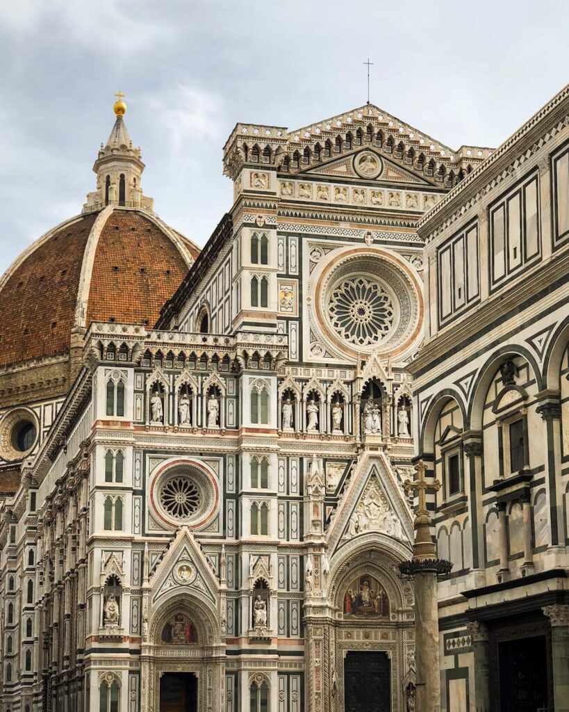The Florence Cathedral facade, with the baptistry in front of it and the dome rising behind. The terra cotta dome contrasts beautifully with the pink, white and green marble of the facade.