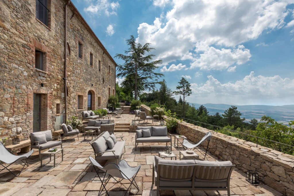 The exterior of Monteverdi Tuscany, a luxury Tuscany hotel, with a beautiful outdoor terrace overlooking the Tuscan countryside