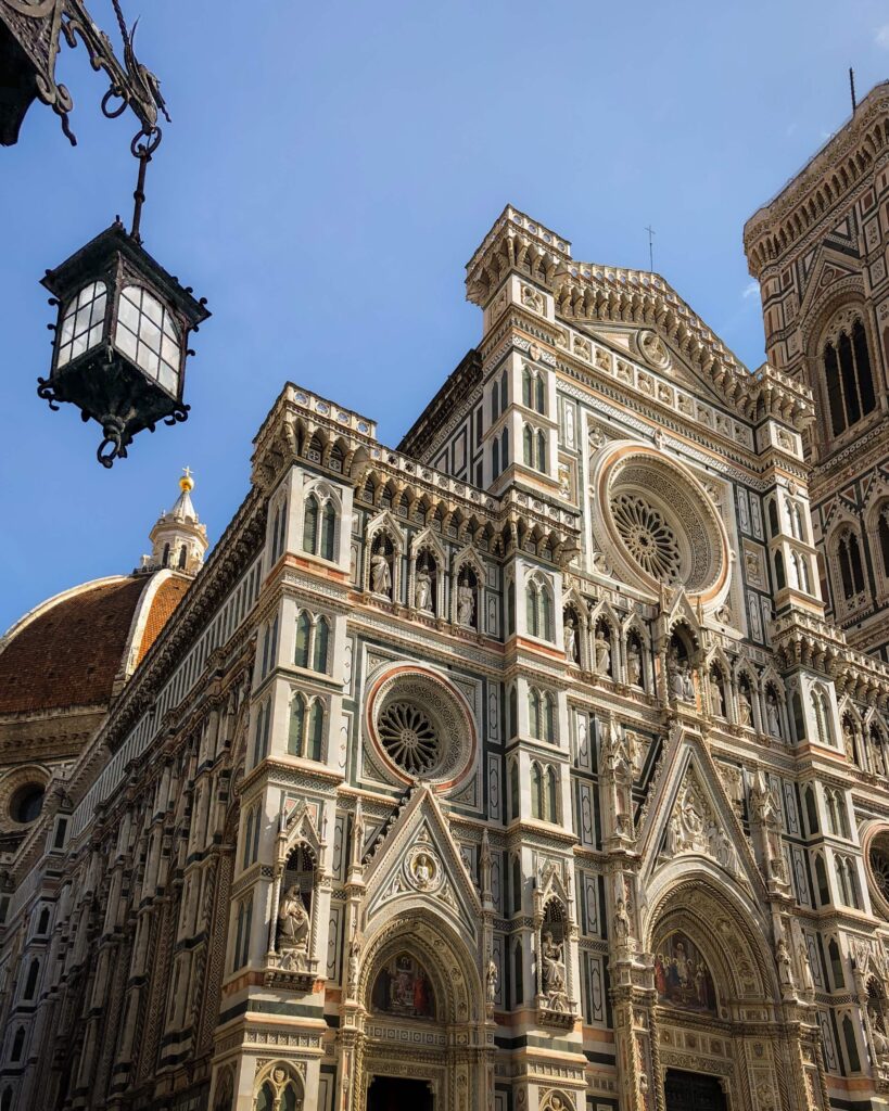 The facade of the Florence Cathedral, in pink, green and white marble, with the bell tower rising next to it