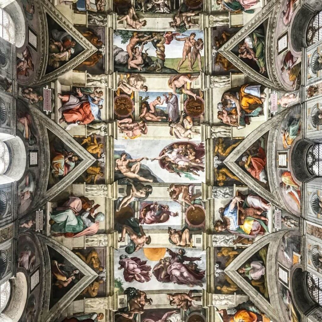 The ceiling of the Sistine Chapel, with Michelangelo's frescoes. In the center is the most famous fresco, The Creation of Adam, with the fingers of Adam and God touching.
