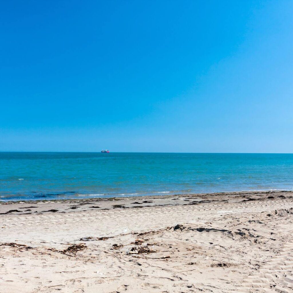 Sand and ocean at Sottomarina Beach near Chioggia Italy. A ship can be seen in the distance.