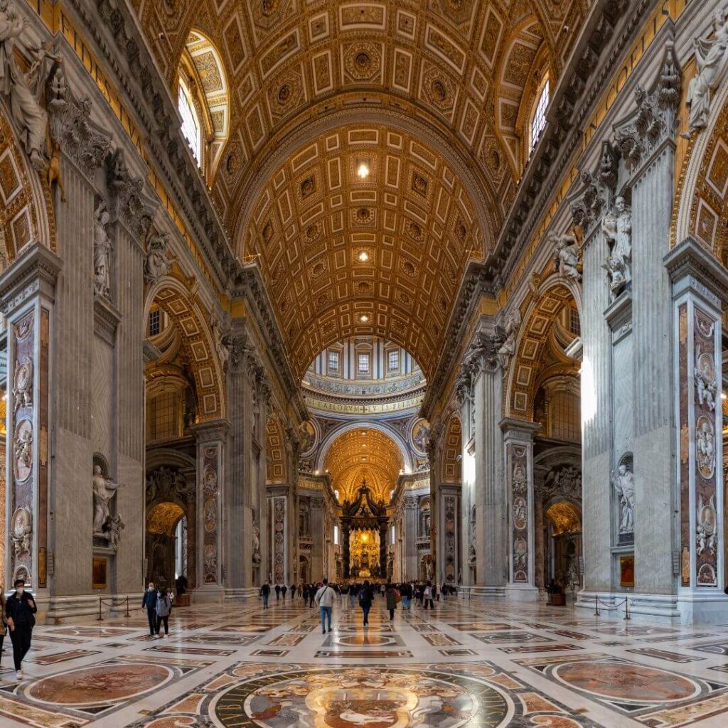 The interior of St. Peter's Bascilica in Vatican City, Rome, Italy. There are richly colored marble mosaics, so detailed they look like paintings, highlighting the details on the floor, walls and ceiling.