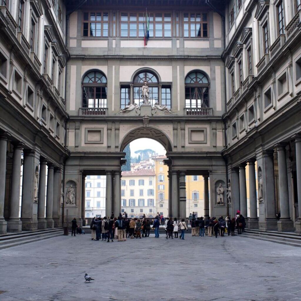 The courtyard of the Uffizi Gallery in Florence, Italy. Tour groups are just starting to gather, and you can see the statues of important Florantine citizens that the courtyard is famous for in niches around the sides.