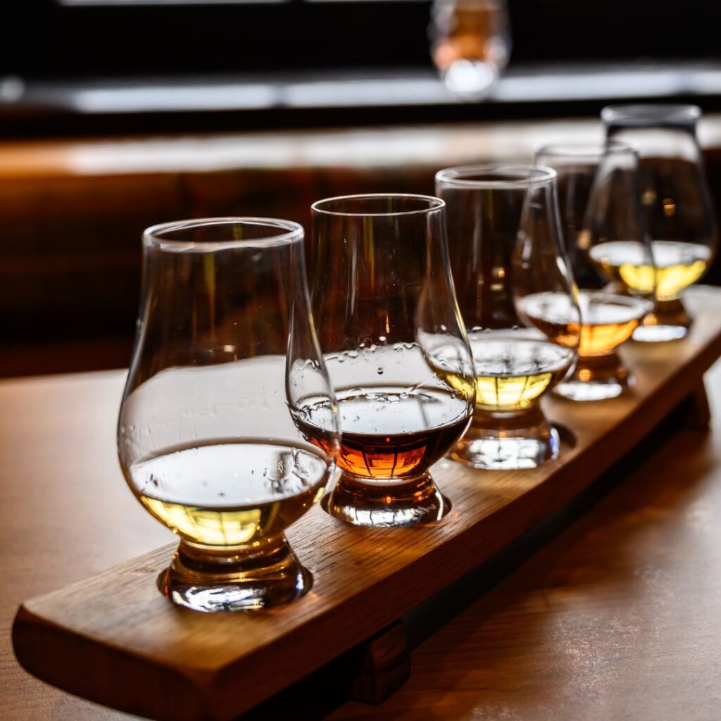 Scotch whisky in clear glasses on a wooden tray in a tasting flight