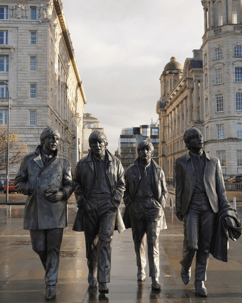 Bronze statue of The Beatles at Pier Head, Liverpool, with the Three Graces in the background