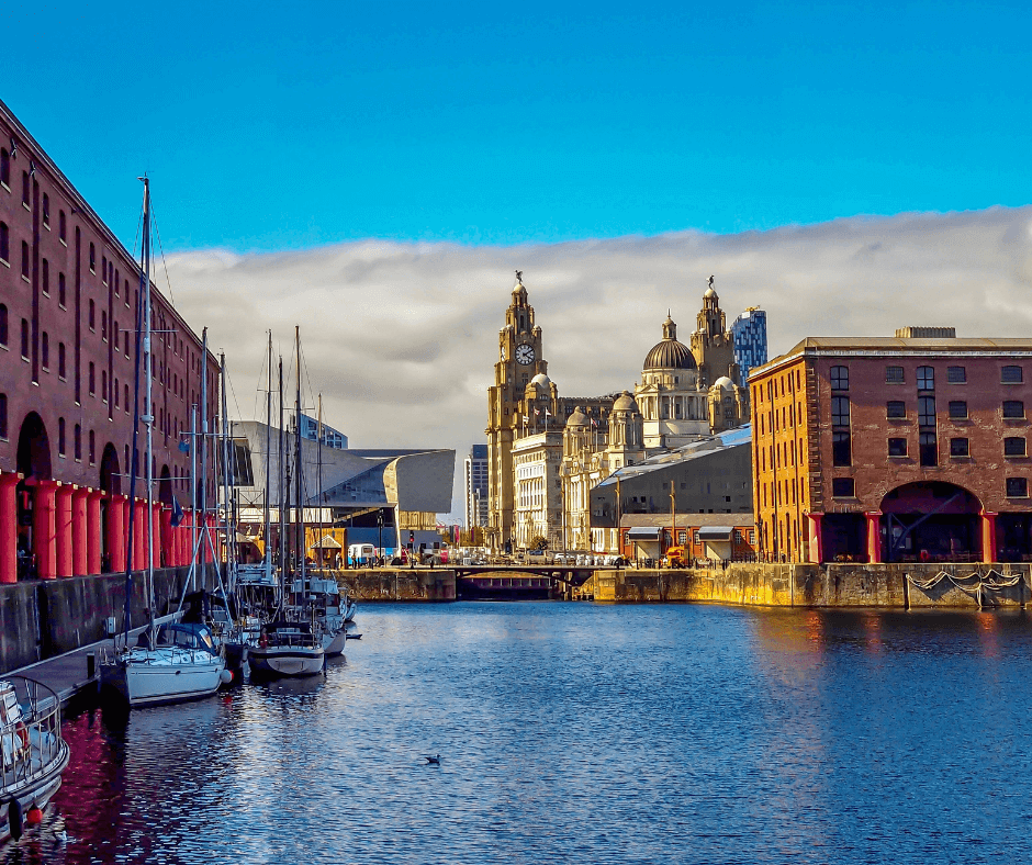 View of Liverpool city skyline from Royal Albert Dock with moored boats and brick warehouses