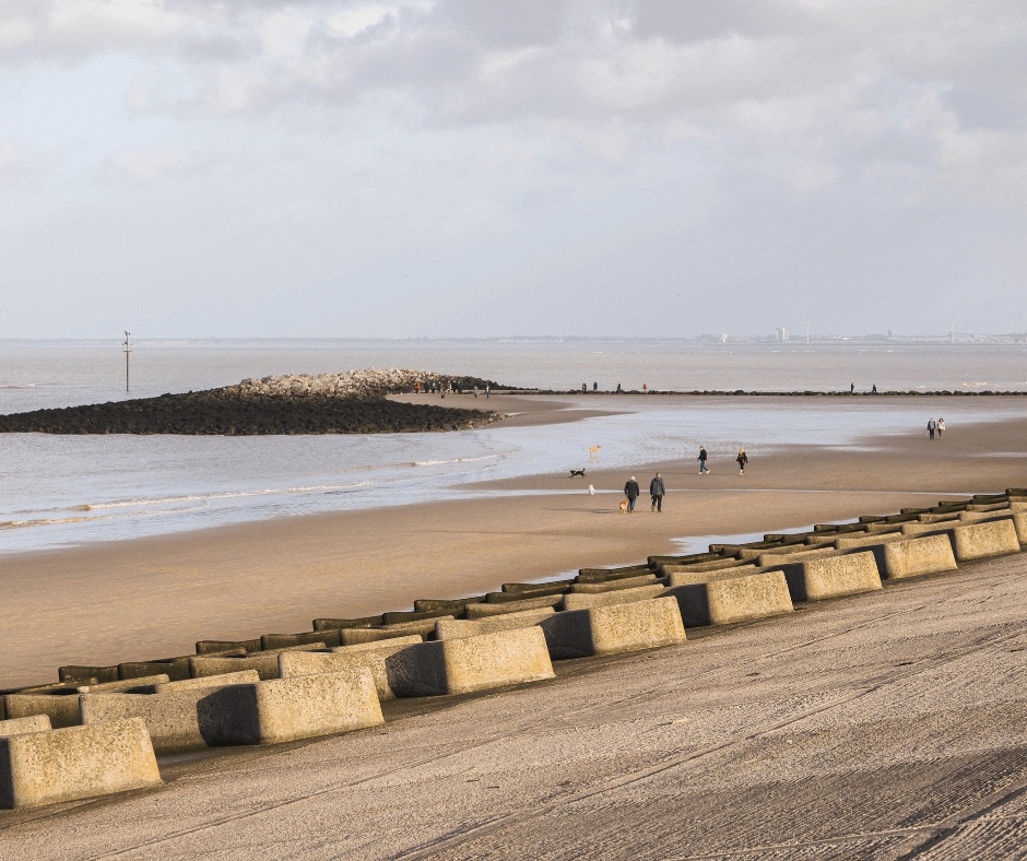 People walking along New Brighton Beach on the Wirral, one of Liverpool’s famous filming locations featured in Florence Foster Jenkins and Peaky Blinders.