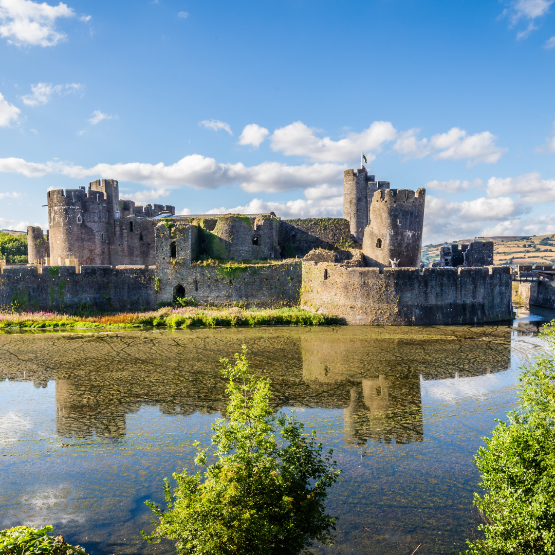 Caerphilly Castle, located in South Wales, with its reflection in the moat surrounding the castle.