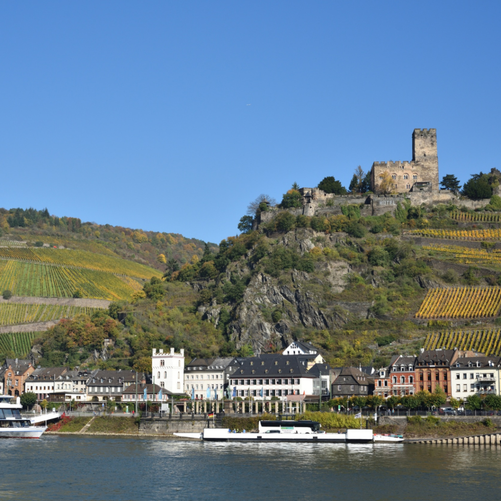 A castle on a hill over the Rhine River valley in Germany with a town below
