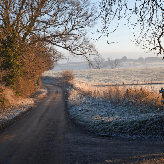 A rural Cotswolds lane with a heavy winter frost