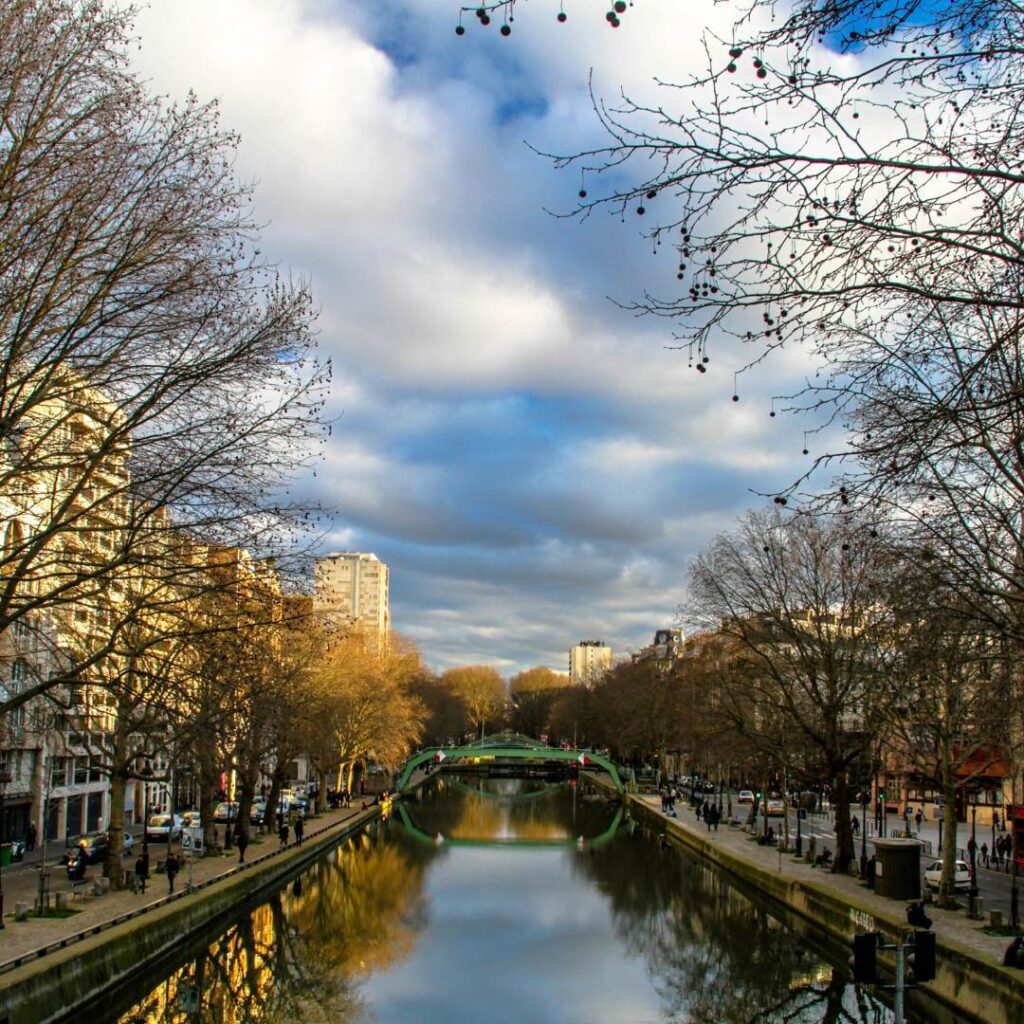 Tree-lined Canal Saint-Martin with blue skies and puffy clouds in the 10th Arrondissement