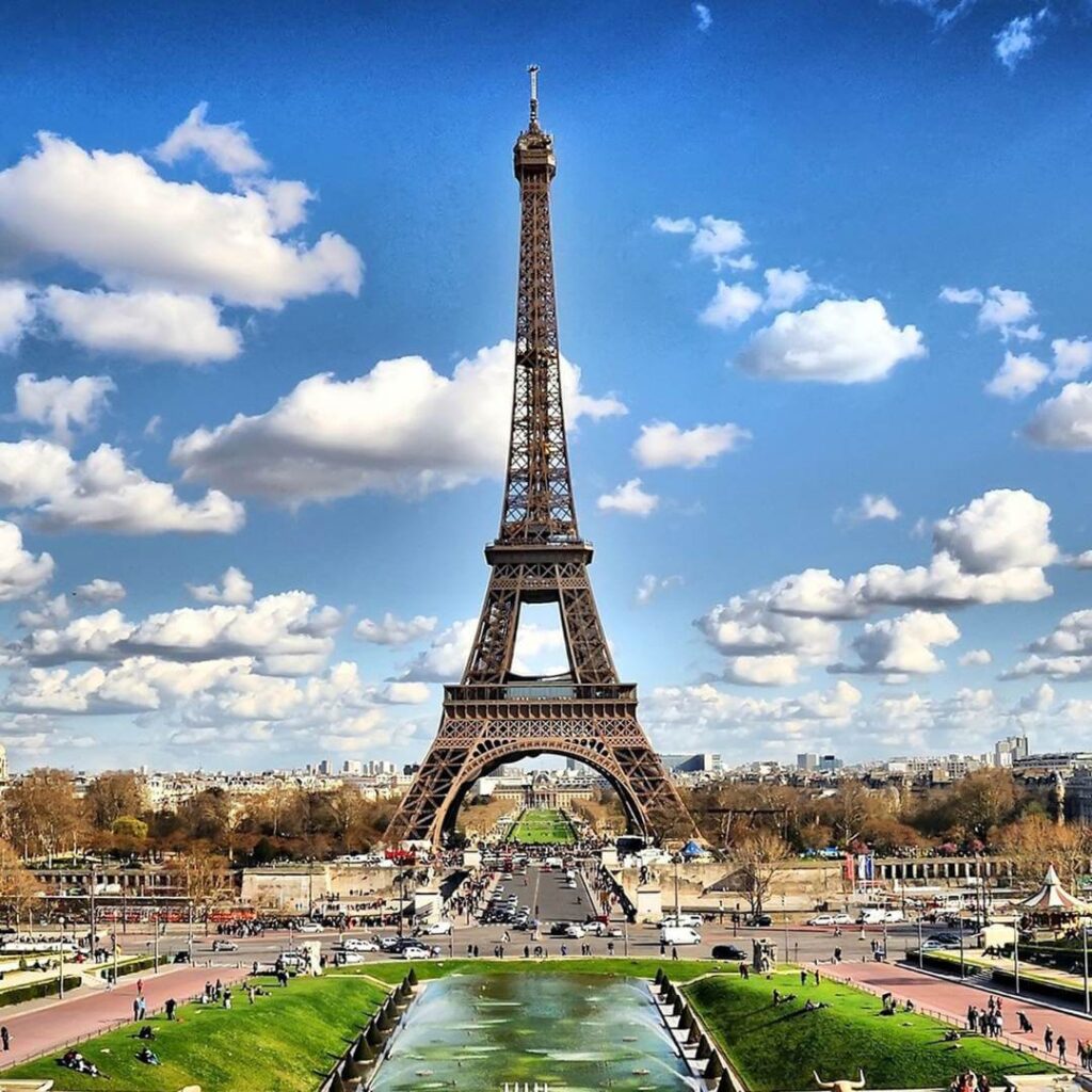 The Eiffel Tower against a blue sky filled with puffy white clouds