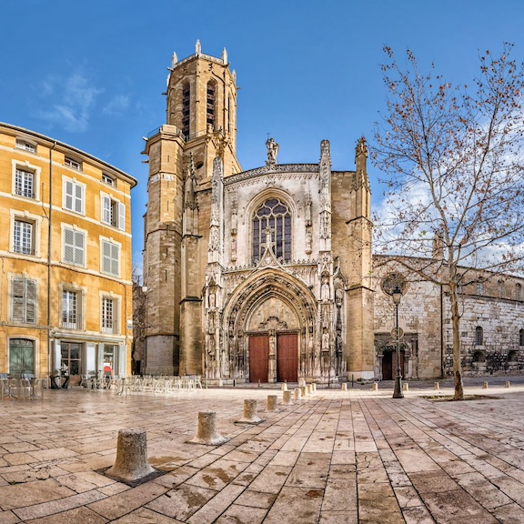 The front of the Aix cathedral across a cobbled square framed against a bright blue sky, one of the most common things to do in Aix-en-Provence