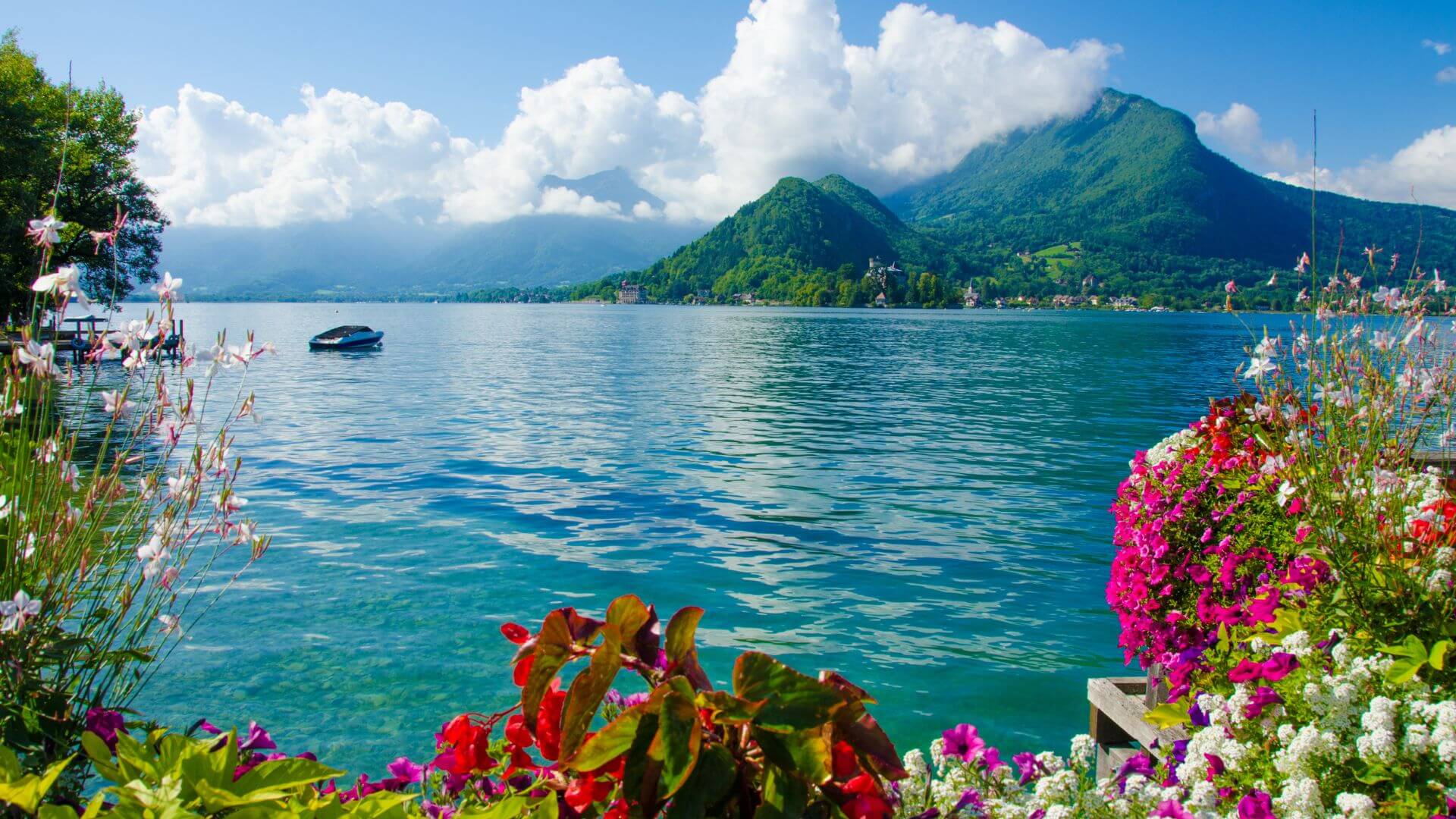 A view across a lake in France with cloud covered mountains in the background