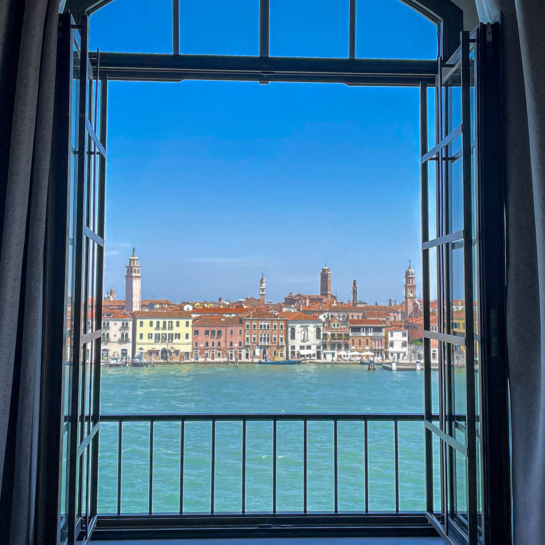 Looking out an open window across the water at the buildings of Venice