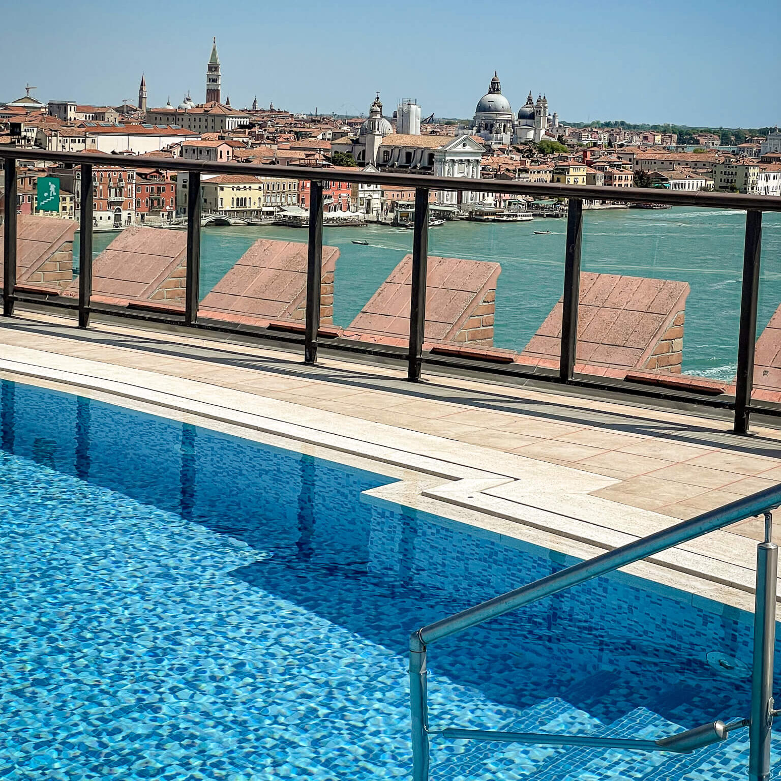 Rooftop pool at the Hilton Molino Stucky Venice hotel, looking across the pool chairs with the island of Venice in the background