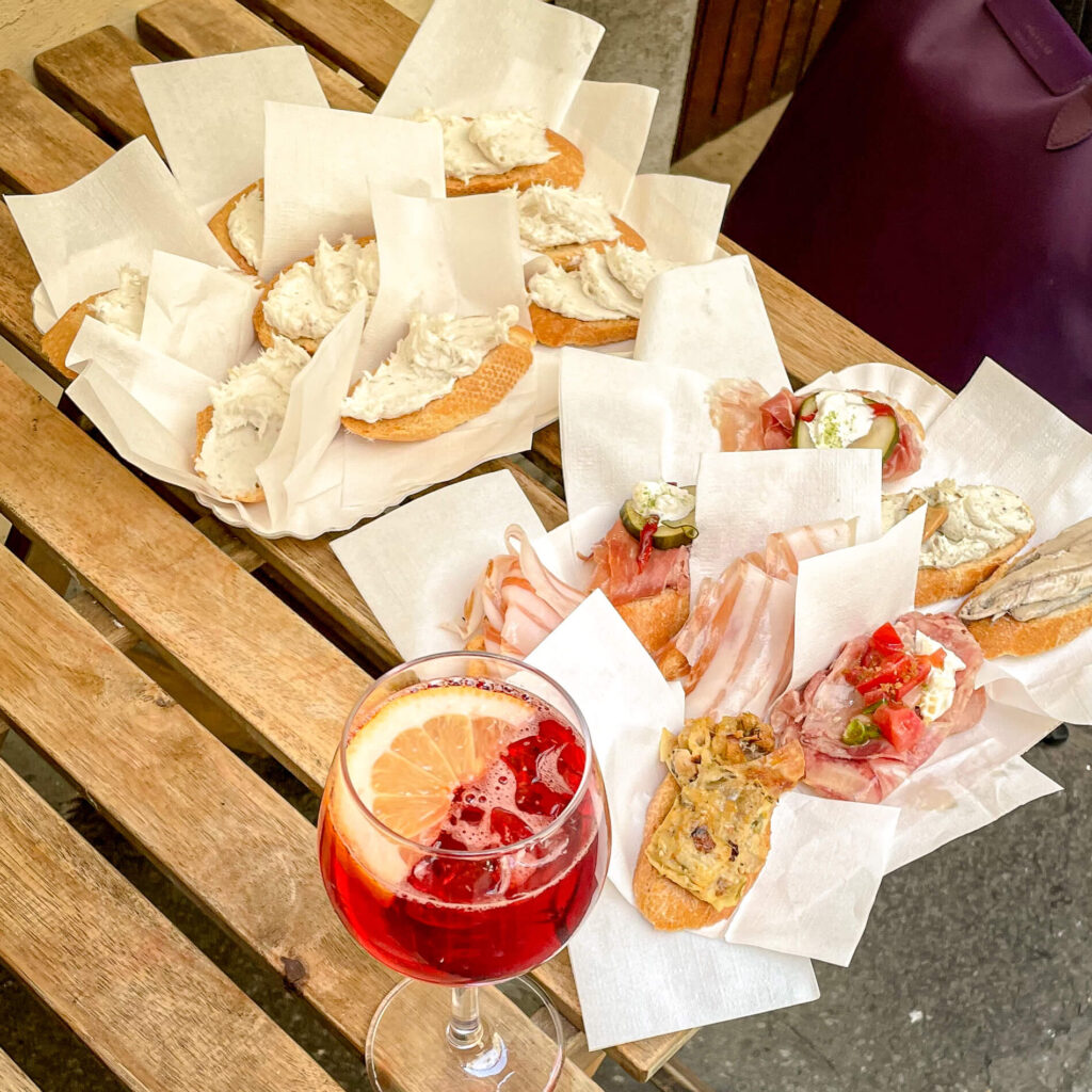 Multiple samples of cicchetti on a table with a drink nearby