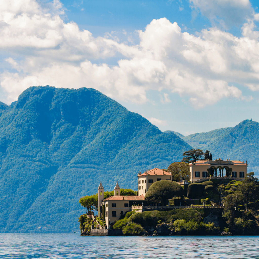 A villa on the shore of the blue waters of Lake Como with green mountains rising in the background in Lombardy, one of the most famous regions of Italy