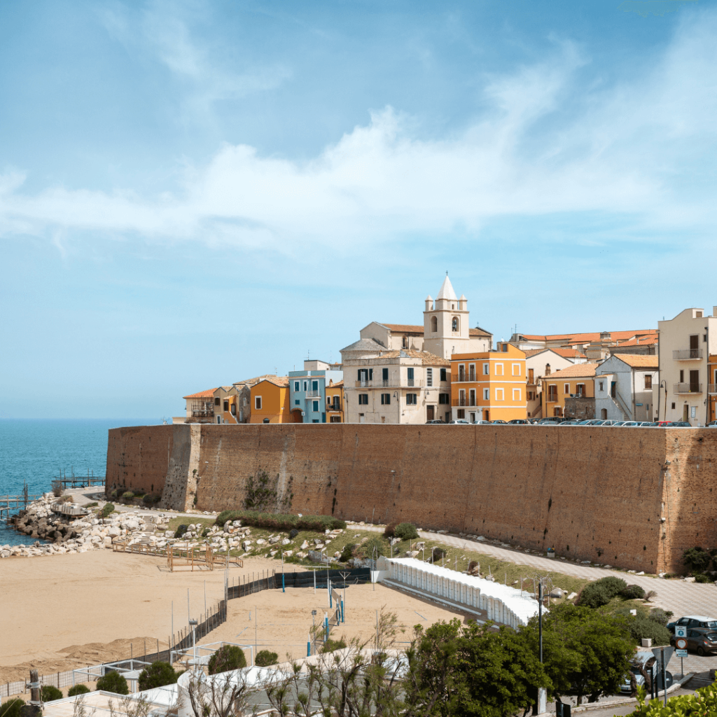 The seawall of Termoli with the town beyond, rising above white sandy beaches and the blue waters of the Mediterranean