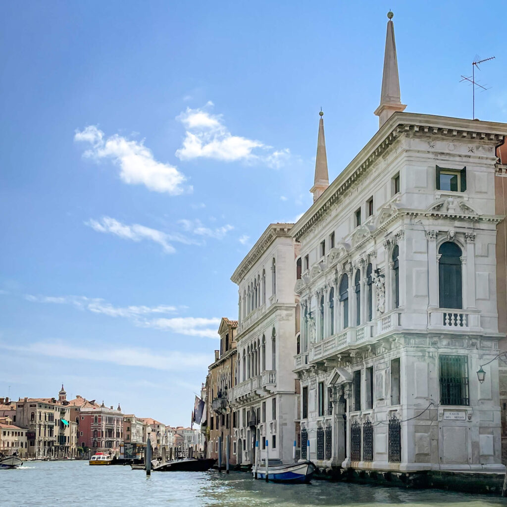 The canal-side view of the palazzos along Venice's grand canal, silhouetted against a bright blue sky