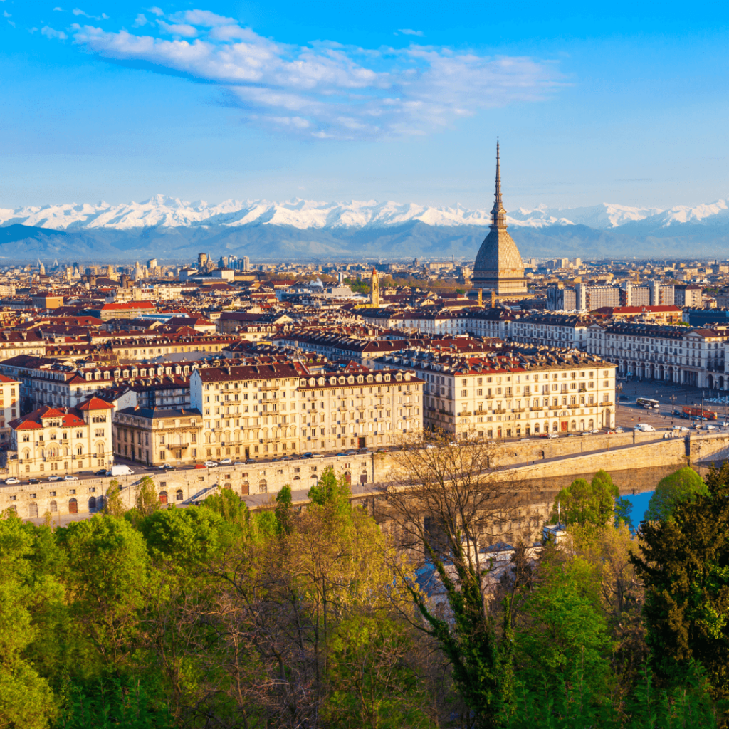 An aerial view of the tan buildings and red roofs spread across the city of Turin