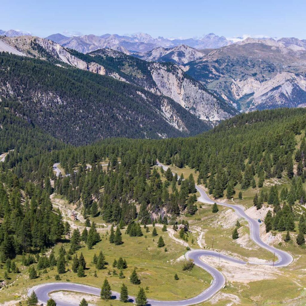 Winding mountain pass road Col D'Izoard through the green trees on the Route des Grandes Alpes, one of the scenic drives in france