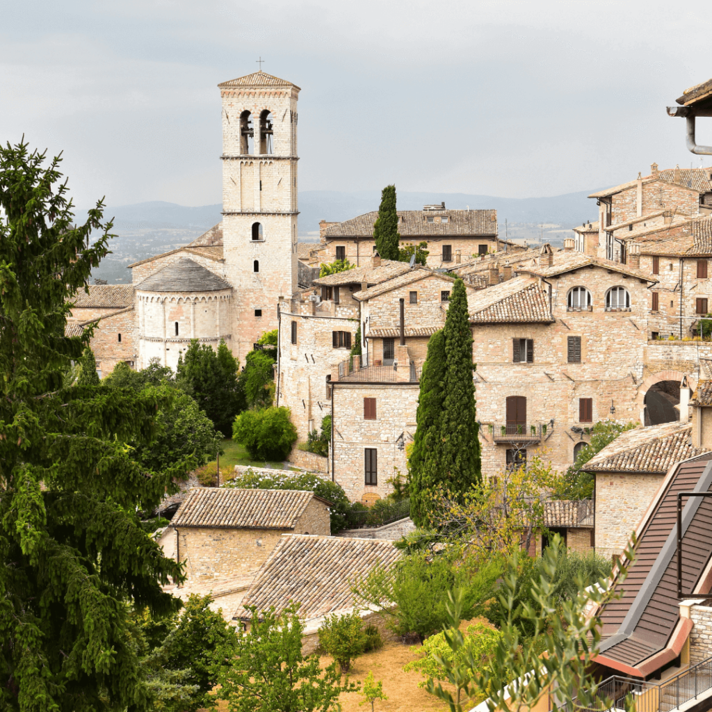 White stone buildings with the belltower rising from the skyline of Assisi in Umbria, one of the regions of Italy