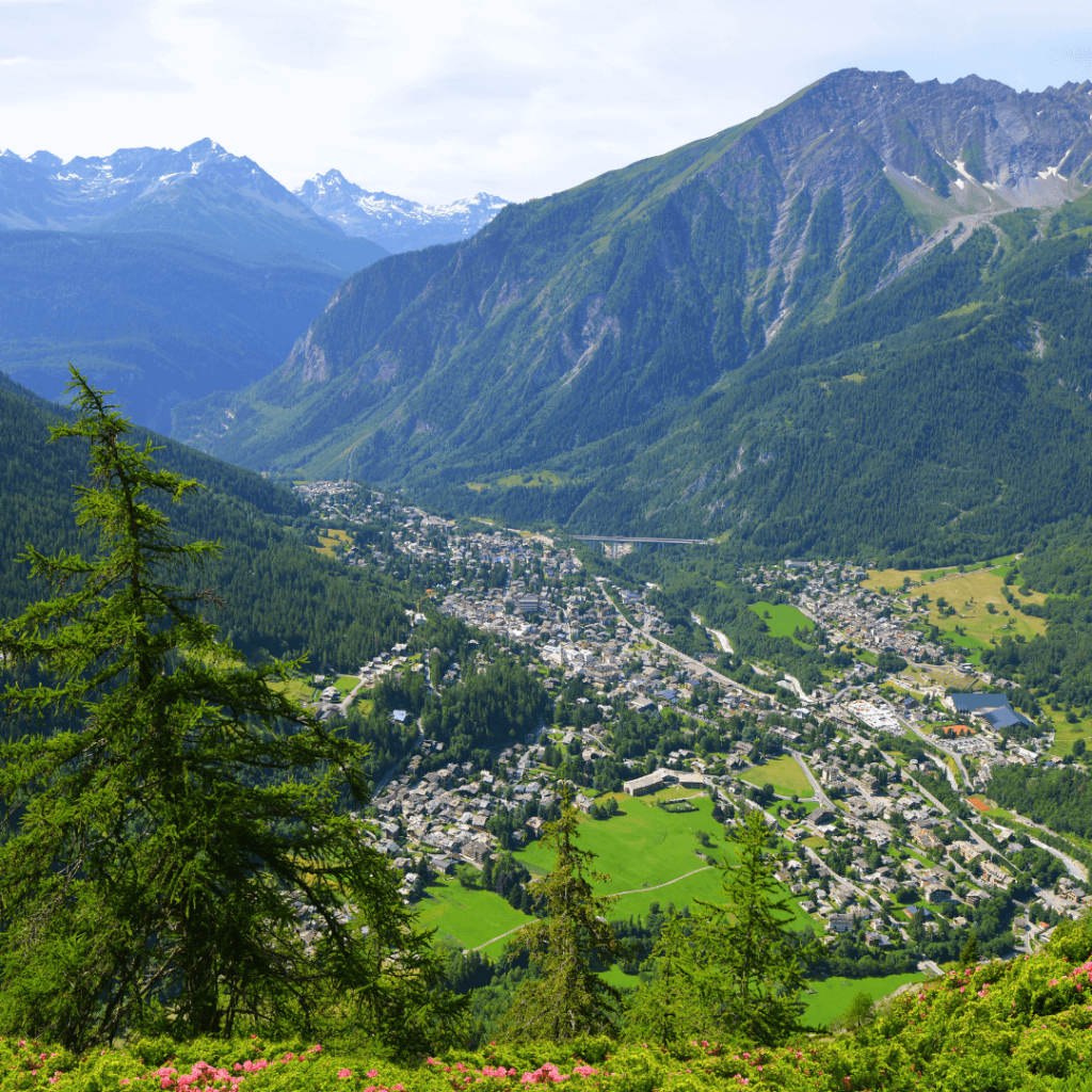 Looking down at the village of Courmayeur nestled in the valley with alpine mountains rising on each side in Valle d'Aosta, one of the regions of Italy