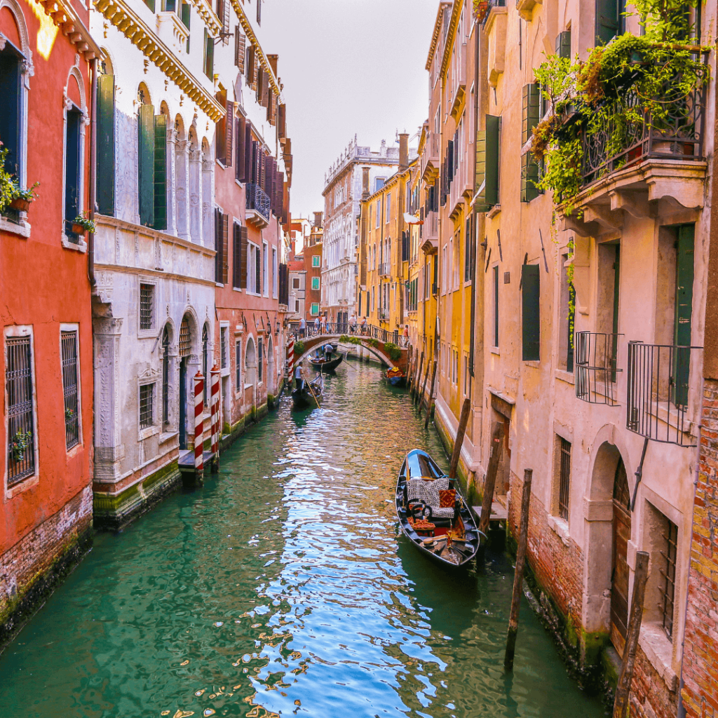 Looking down a canal from a bridge with buildings lining each side and boats in the Venetian canal