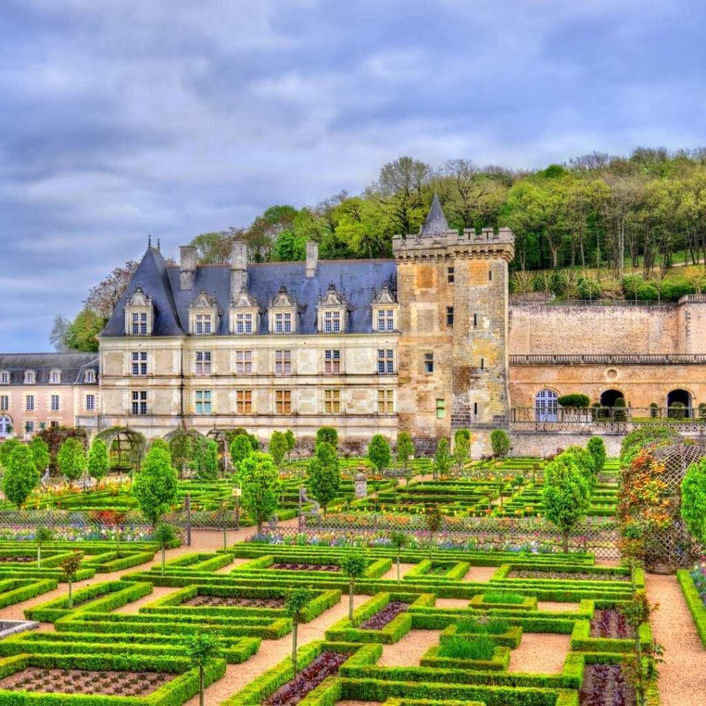 The gardens at Chateau de Villandry with the chateau in the background against a blue sky