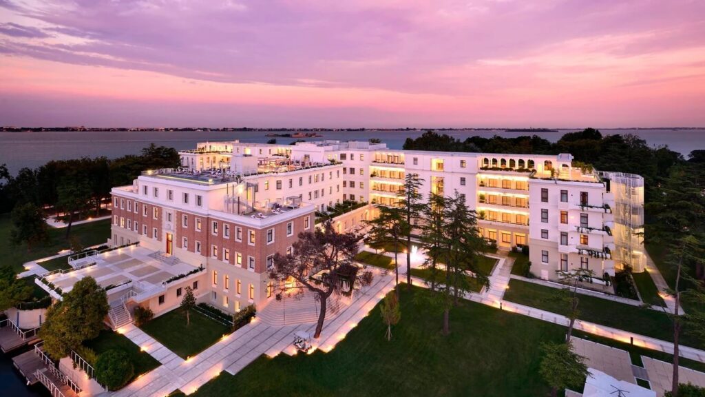 Aerial view of the exterior of the JW Marriott Venice hotel against a pink sunset sky, one of the luxury hotels in Venice Italy